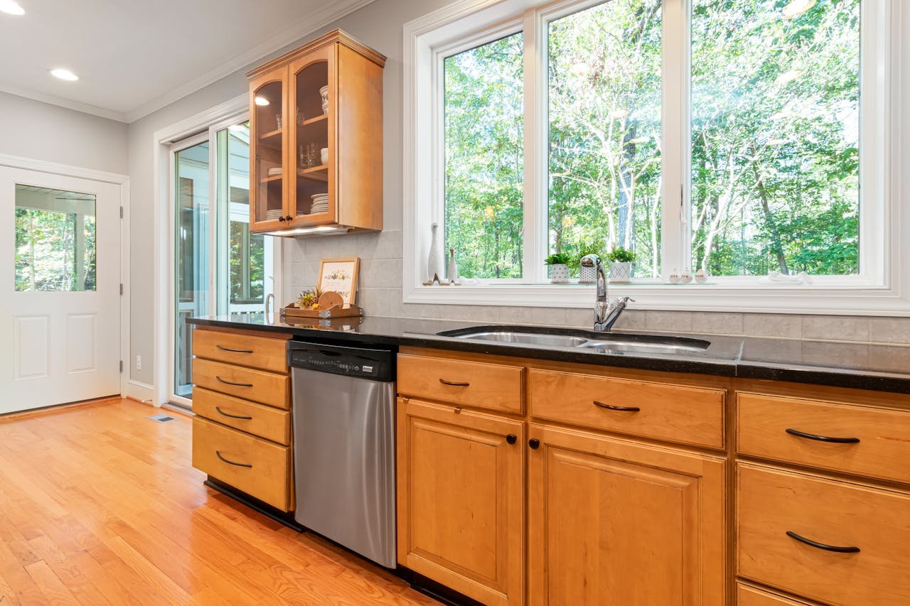 Home Spacious kitchen featuring wooden cabinets, large windows, and a stainless steel dishwasher.