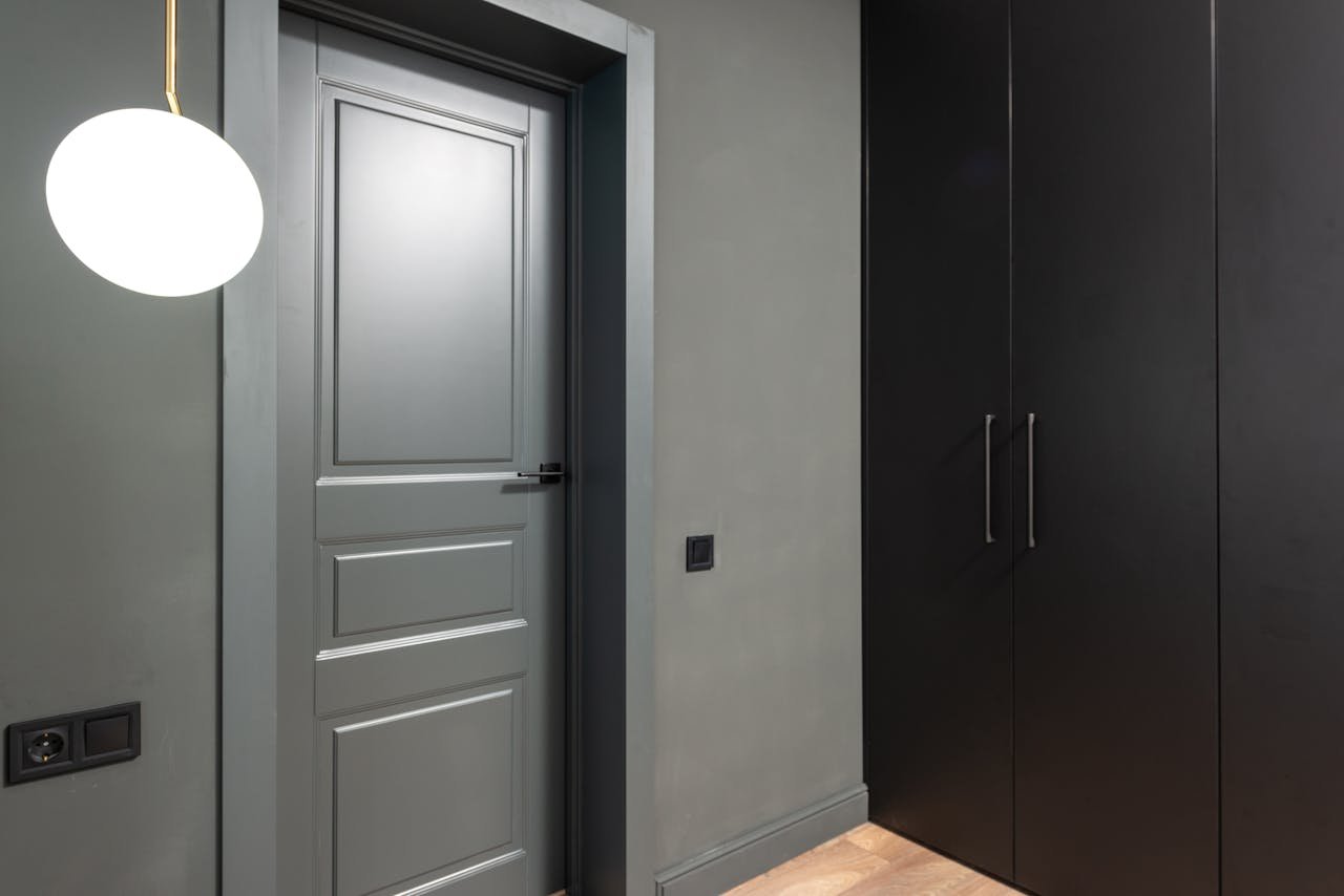 Stylish interior with a minimalist wardrobe, grey door, and modern lighting fixture.